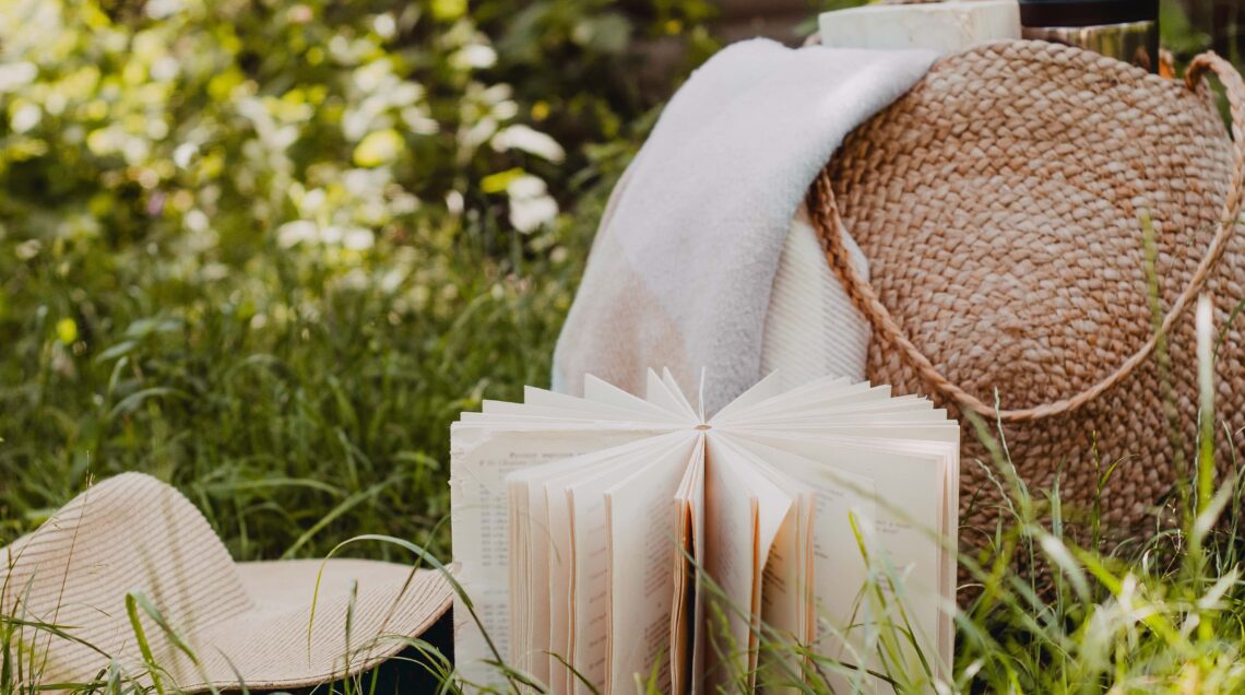 Straw bag, book, hat on a sunny summer day.