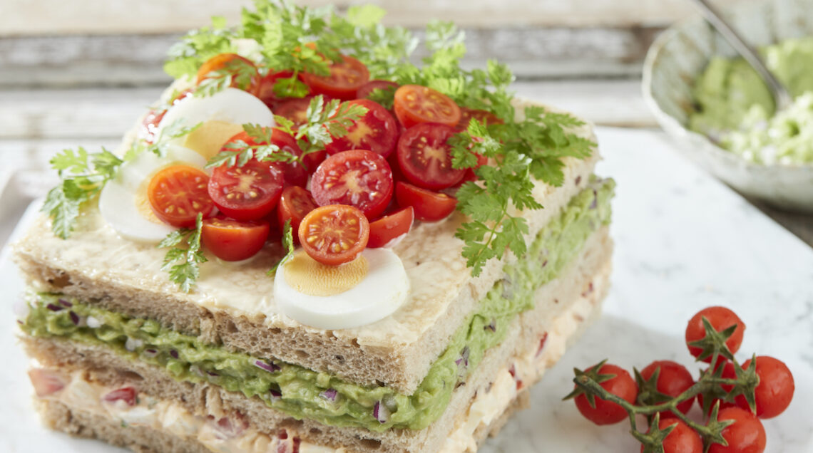 Torta sandwich di avocado, pomodorini e uova sode. Pane bianco a strati con crema diavocado coi pomodorini e mix di uova sode con maionese, yogurt e aneto. Volendo anchecon trota salmonata affumicata