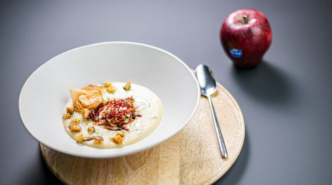 Crema di Red Delicious e sedano con uovo in camicia, scaglie di prosciutto e fiori di mela