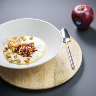 Crema di Red Delicious e sedano con uovo in camicia, scaglie di prosciutto e fiori di mela